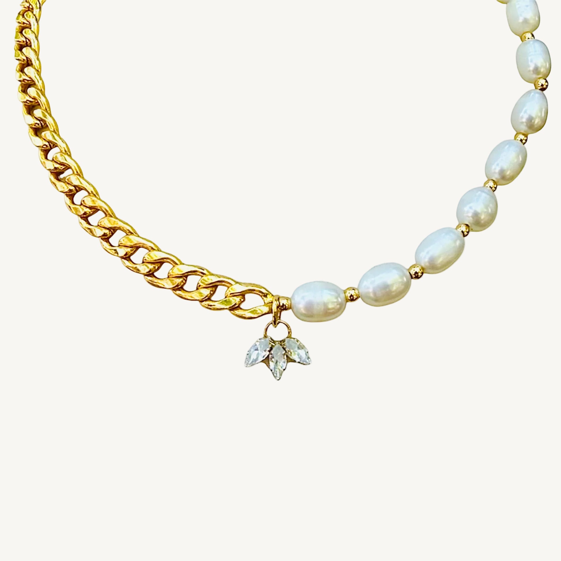 Gold chain necklace with pearl beads and a diamond pendant on a white background
