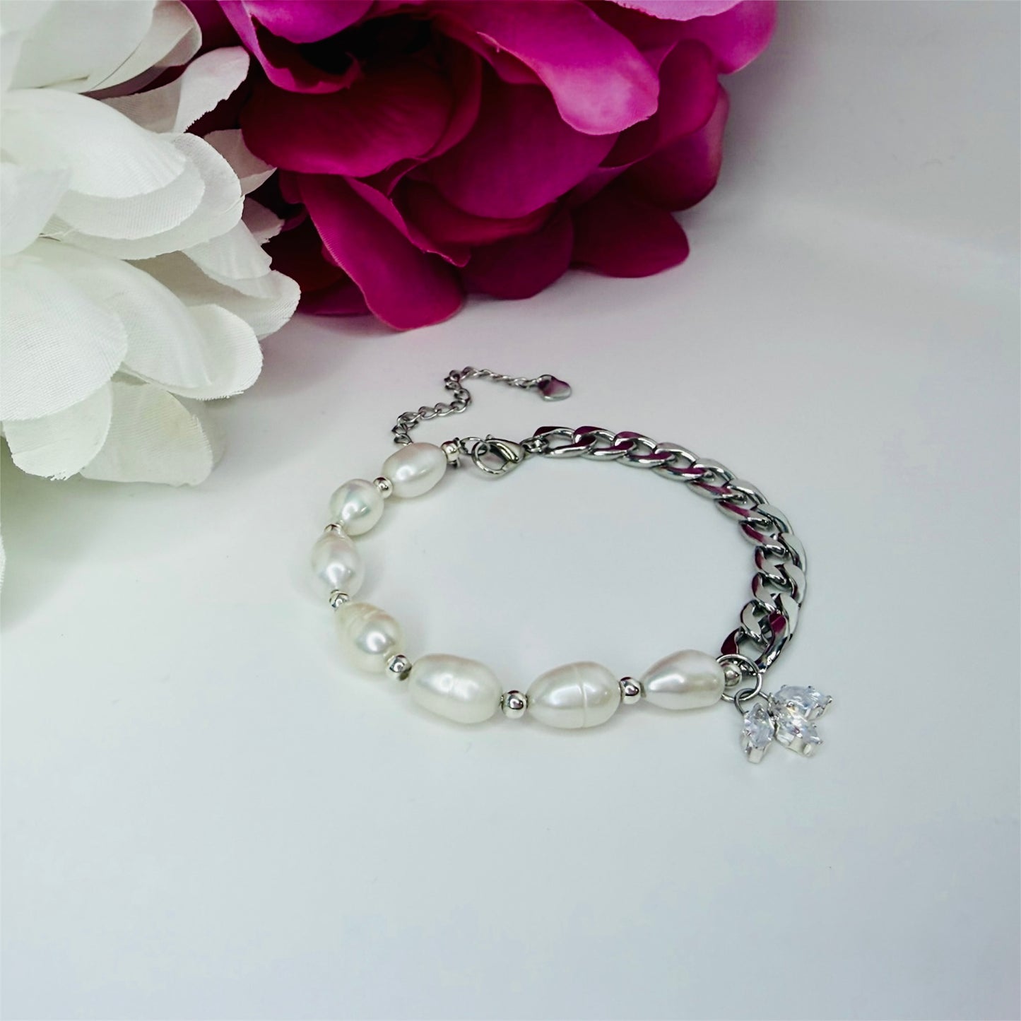 Bracelet with natural freshwater pearls and cuban chain on a white surface with pink and white flowers